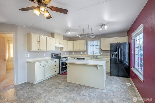 kitchen featuring black fridge with ice dispenser, sink, a center island, ceiling fan, and range with two ovens