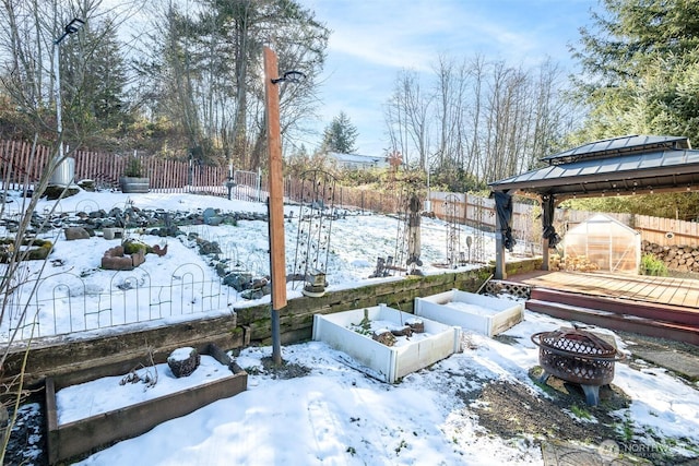 snowy yard with a gazebo, an outdoor fire pit, and an outdoor structure