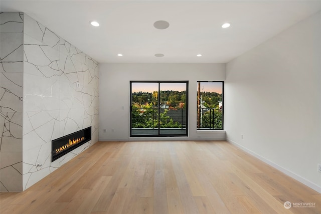 unfurnished living room featuring light hardwood / wood-style floors and a tile fireplace