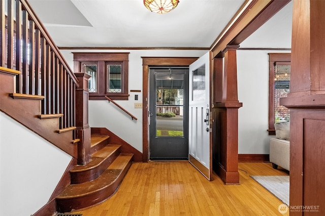 foyer with light wood-type flooring and crown molding