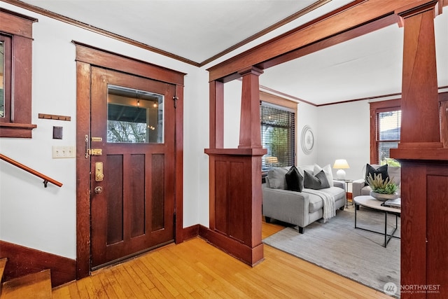 foyer featuring decorative columns, ornamental molding, and light hardwood / wood-style flooring