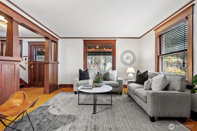 living room with decorative columns, ornamental molding, a healthy amount of sunlight, and light hardwood / wood-style flooring