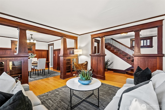 living room featuring decorative columns, ornamental molding, and light hardwood / wood-style flooring