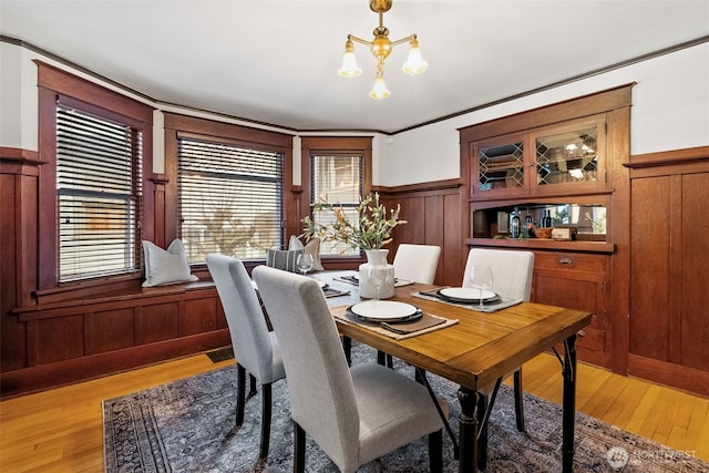 dining room with hardwood / wood-style flooring, crown molding, and a notable chandelier