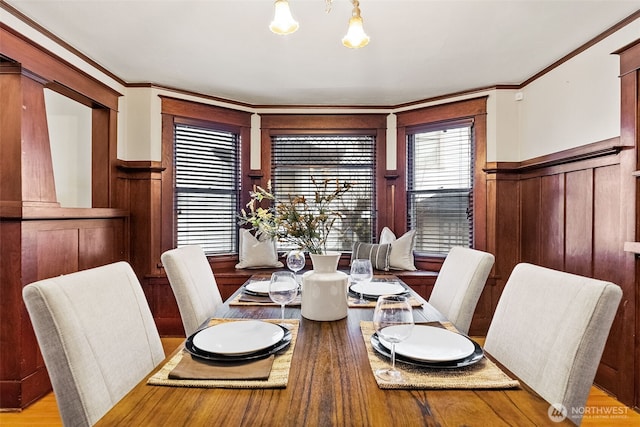 dining space with light hardwood / wood-style floors, a chandelier, and ornamental molding