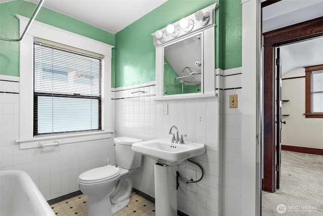 bathroom featuring toilet, tile walls, and a bathtub