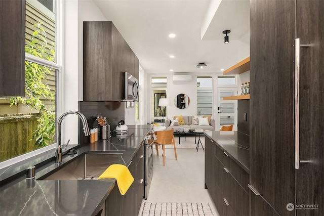 kitchen with dark brown cabinetry, appliances with stainless steel finishes, sink, and a wall unit AC