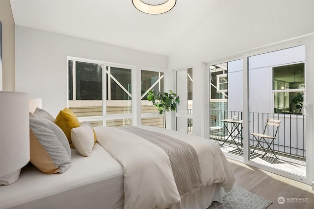 bedroom featuring hardwood / wood-style flooring, lofted ceiling, and access to exterior