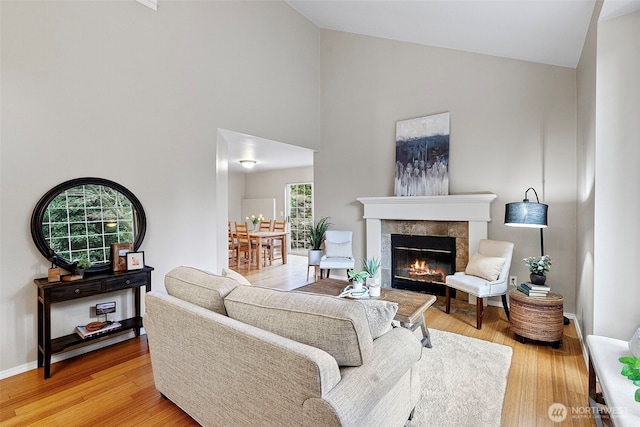 living room featuring hardwood / wood-style floors, a tile fireplace, and high vaulted ceiling