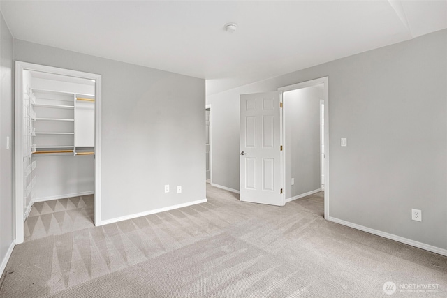 unfurnished bedroom with a spacious closet and light colored carpet