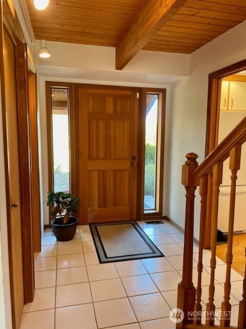 foyer entrance featuring light tile patterned floors, beamed ceiling, and wooden ceiling