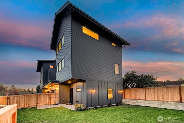 back house at dusk featuring a lawn