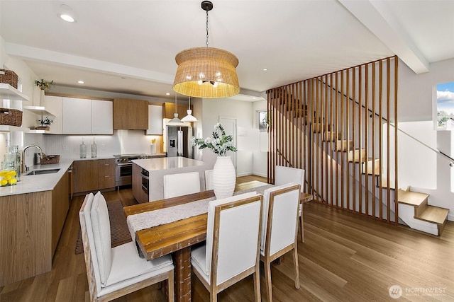 dining room featuring beam ceiling, sink, and light wood-type flooring