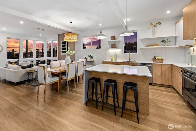 kitchen featuring a kitchen island, pendant lighting, a kitchen bar, stainless steel appliances, and light wood-type flooring