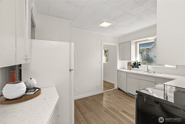 kitchen featuring sink, white cabinetry, white refrigerator, ornamental molding, and light hardwood / wood-style floors