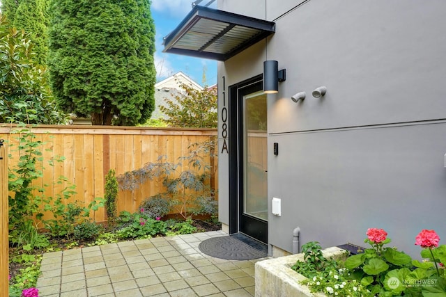 exterior space featuring a patio area, fence, and stucco siding