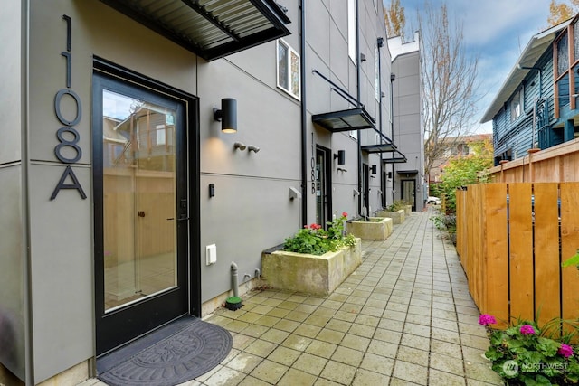 doorway to property featuring fence and stucco siding