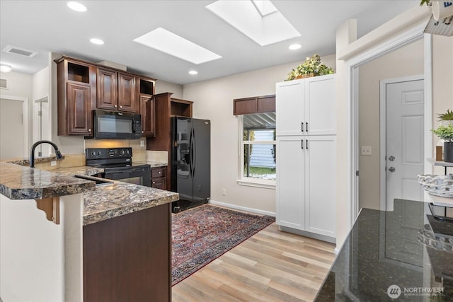 kitchen featuring visible vents, a peninsula, black appliances, and open shelves