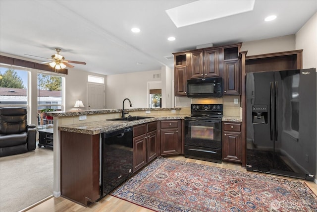 kitchen with black appliances, dark brown cabinets, a peninsula, and a sink