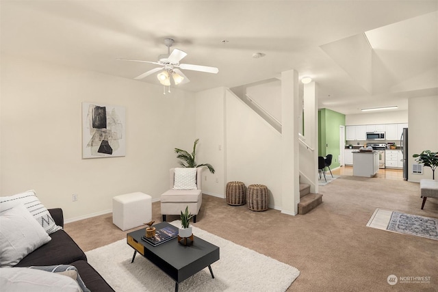 living area featuring light carpet, baseboards, stairway, and a ceiling fan