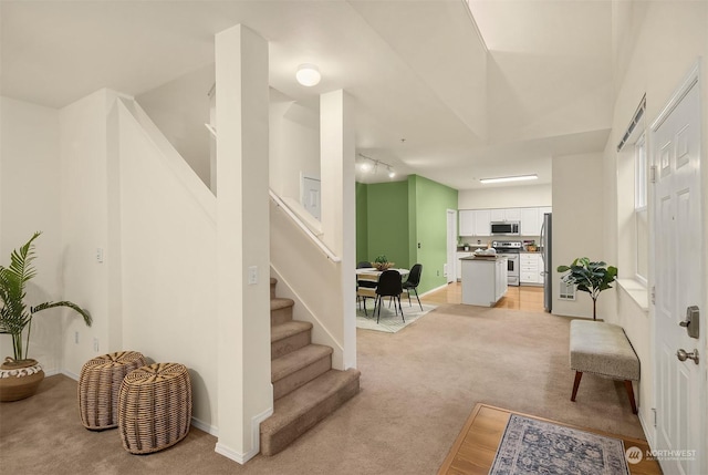 living room with light carpet, baseboards, and stairs