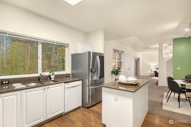 kitchen with dark stone counters, a sink, white cabinetry, dishwasher, and stainless steel fridge