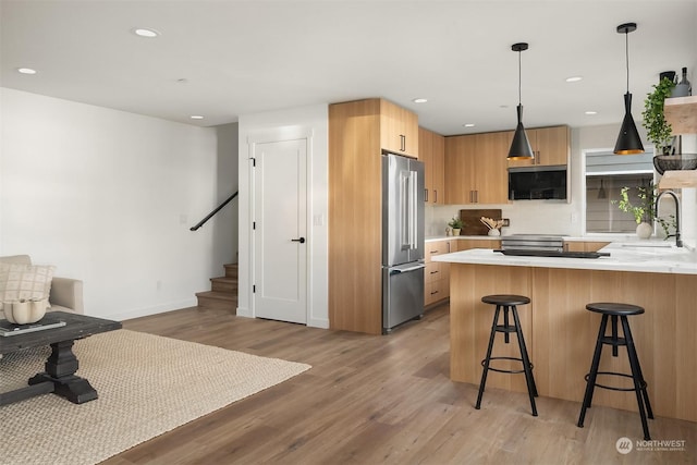 kitchen with a breakfast bar, pendant lighting, sink, high end refrigerator, and kitchen peninsula