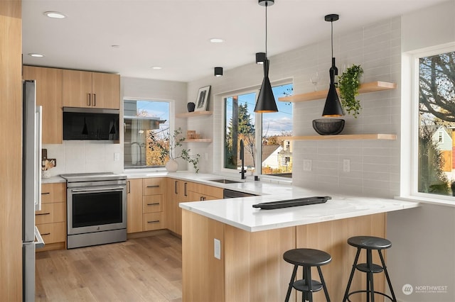 kitchen featuring sink, a breakfast bar, appliances with stainless steel finishes, kitchen peninsula, and light brown cabinets