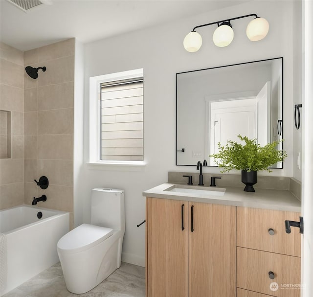 full bathroom featuring vanity, tiled shower / bath, and toilet