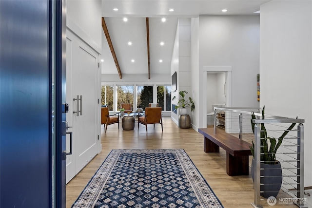 entrance foyer with high vaulted ceiling, beam ceiling, and light hardwood / wood-style floors