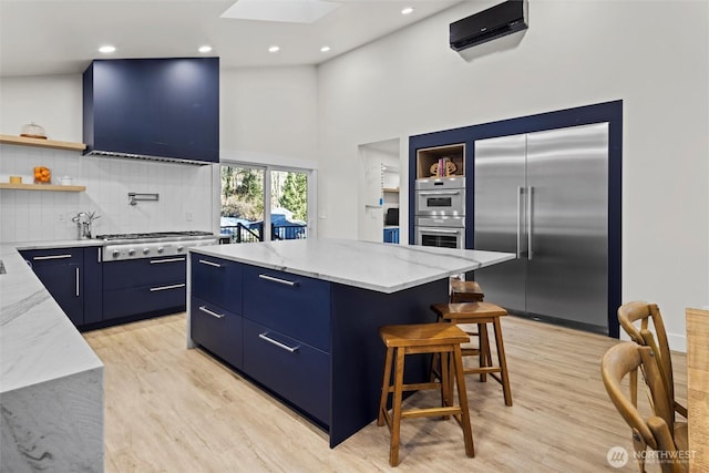 kitchen featuring a kitchen island, blue cabinets, a breakfast bar area, light stone counters, and stainless steel appliances