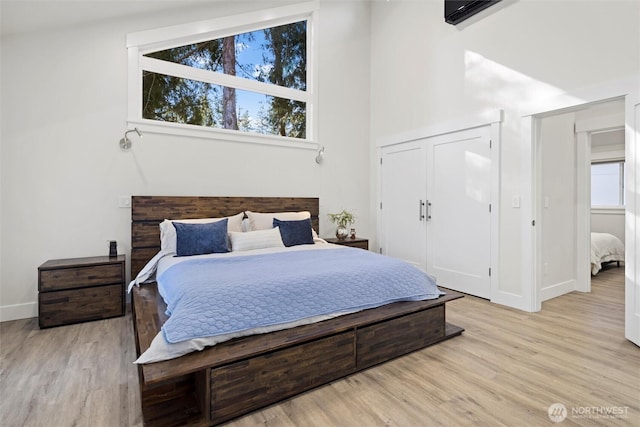 bedroom featuring a high ceiling, light wood-type flooring, and a closet