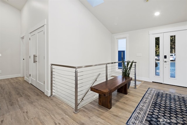 hallway featuring high vaulted ceiling and light hardwood / wood-style flooring