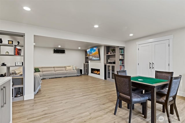 dining room with built in shelves and light wood-type flooring