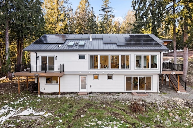 back of property with a deck and solar panels