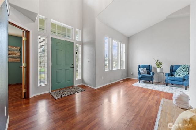 foyer with high vaulted ceiling, baseboards, and wood finished floors