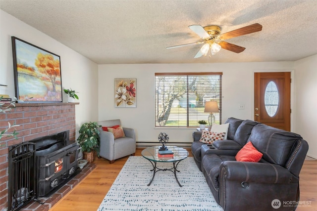 living room featuring a fireplace, ceiling fan, wood-type flooring, and a textured ceiling