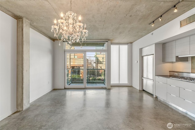 unfurnished dining area featuring a chandelier, visible vents, concrete floors, and baseboards