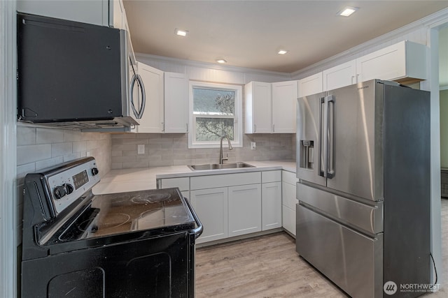 kitchen with sink, tasteful backsplash, light wood-type flooring, stainless steel appliances, and white cabinets