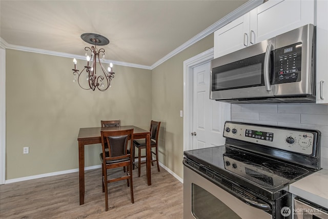 kitchen featuring white cabinets, decorative backsplash, ornamental molding, light hardwood / wood-style floors, and stainless steel appliances