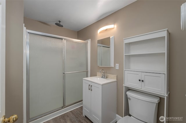 bathroom with a shower with door, vanity, wood-type flooring, and toilet