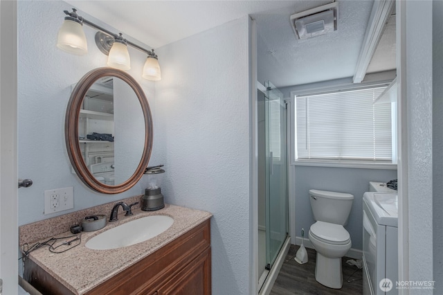 bathroom with vanity, toilet, separate washer and dryer, and a shower with door