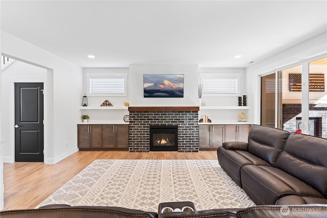 living room with a tiled fireplace and light hardwood / wood-style flooring