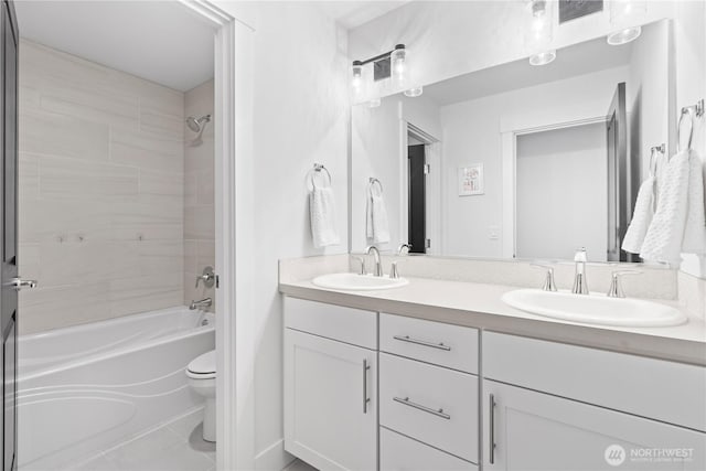 full bathroom featuring tile patterned flooring, tiled shower / bath, vanity, and toilet