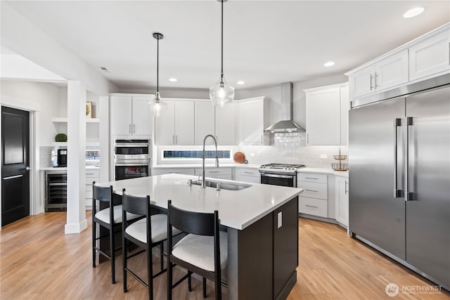 kitchen with wall chimney exhaust hood, sink, stainless steel appliances, beverage cooler, and white cabinets