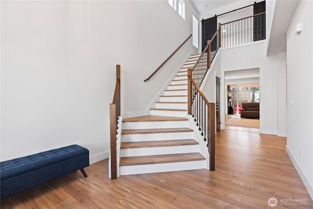 stairs featuring hardwood / wood-style flooring and a towering ceiling