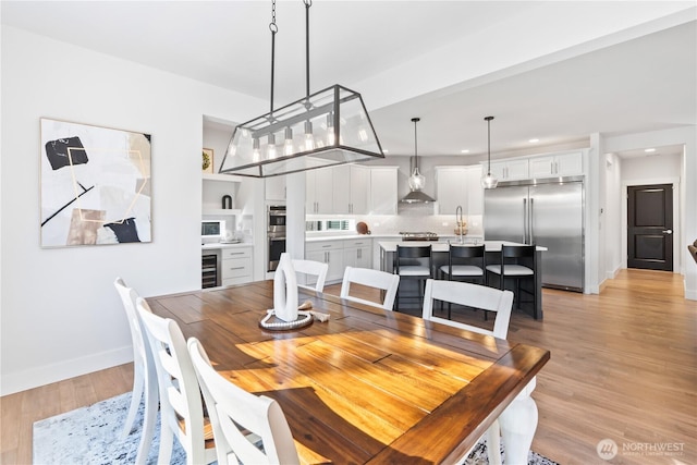 dining room with beverage cooler and light hardwood / wood-style floors