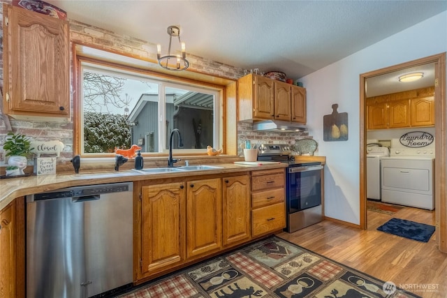 kitchen featuring appliances with stainless steel finishes, sink, independent washer and dryer, a textured ceiling, and light hardwood / wood-style flooring