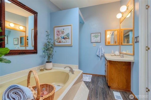 bathroom with hardwood / wood-style flooring, vanity, and a bath