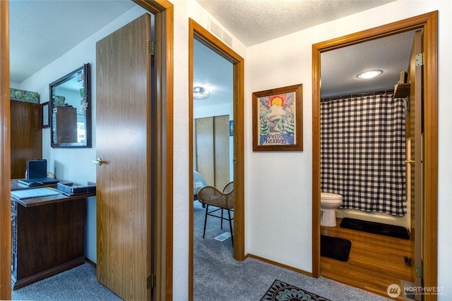 hallway with light colored carpet and a textured ceiling